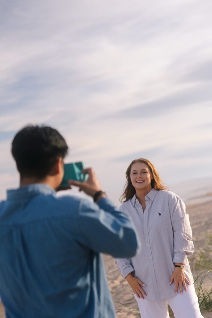 Nick and Katharine taking Polaroid photos during an evening beach date.